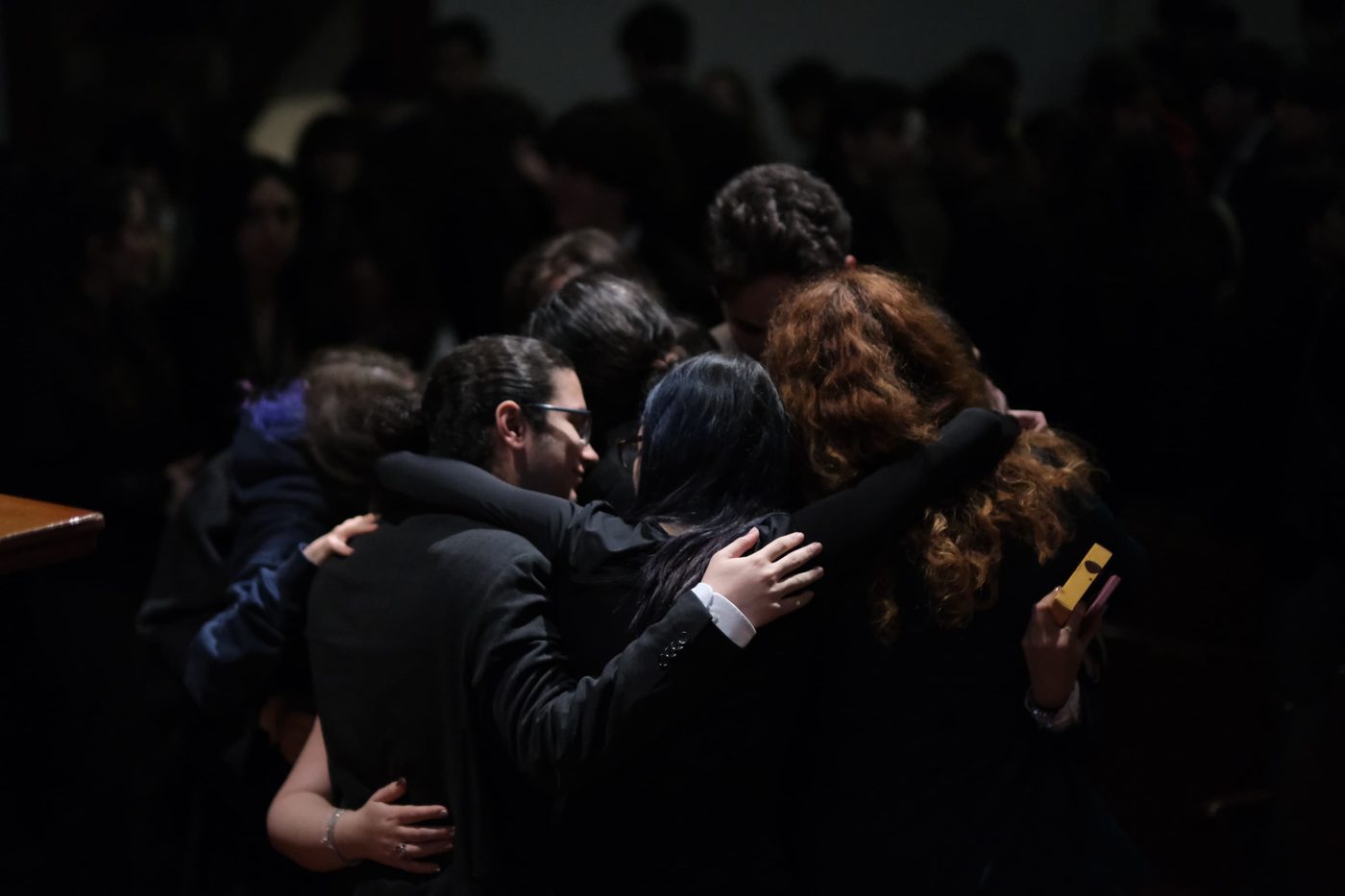 Team members in a group hug on stage at the end of the conference